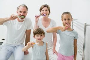 Smiling family of four brushing teeth