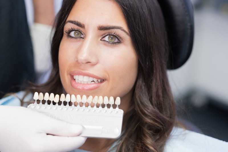 woman having her teeth compared to porcelain veneer samples
