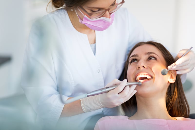 A young brunette woman that is having a dental hygienist examine her teeth.