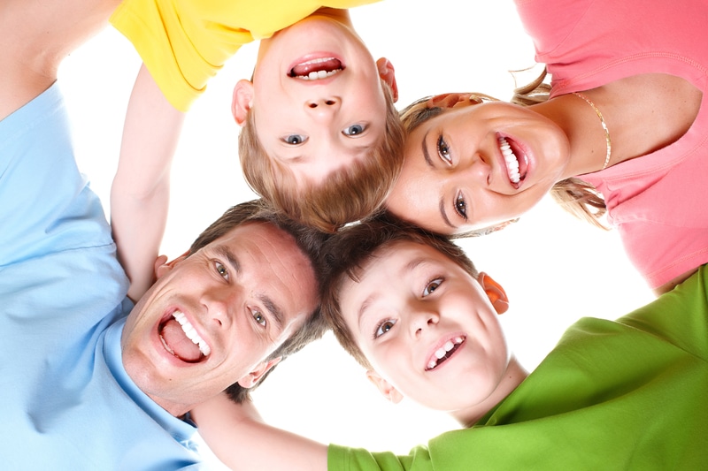 Family in a circle that is smiling and looking down at a camera