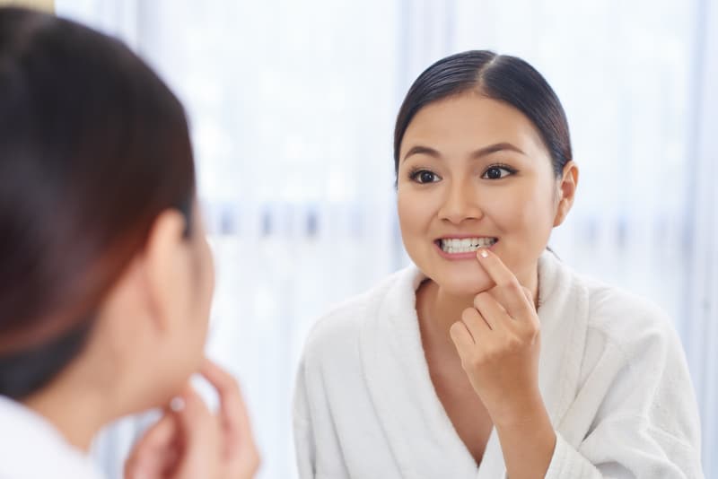 Woman looking into the mirror to see how her gum health is.