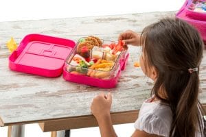 Little girl eating healthy food out of lunchbox