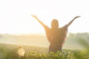 Woman with arms wide open in the air in a sunny field