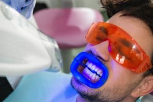 Man in dental chair receiving teeth whitening procedure