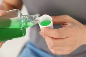 Man pouring mouthwash into a cup