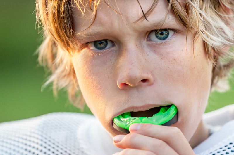 Young boy putting in a mouthguard. 