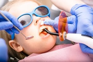 Dentist performing dental filling on a little girl's tooth