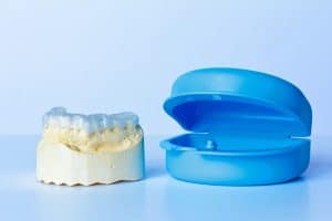 Grind mouthguard on teeth mold sitting by its container.