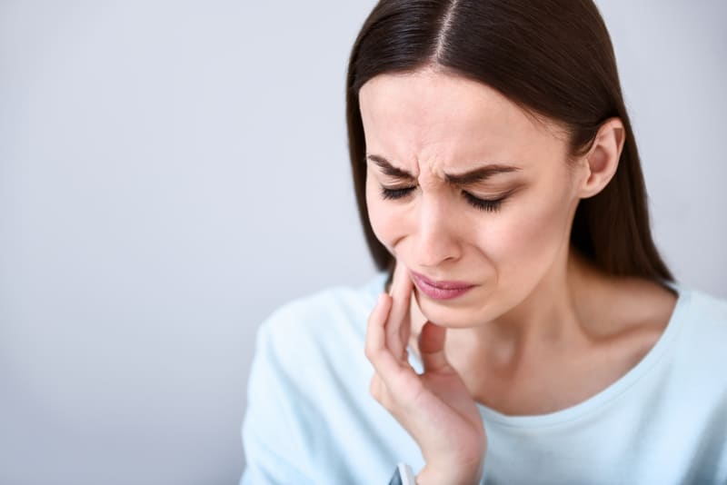 Woman holding jaw with her hand in pain